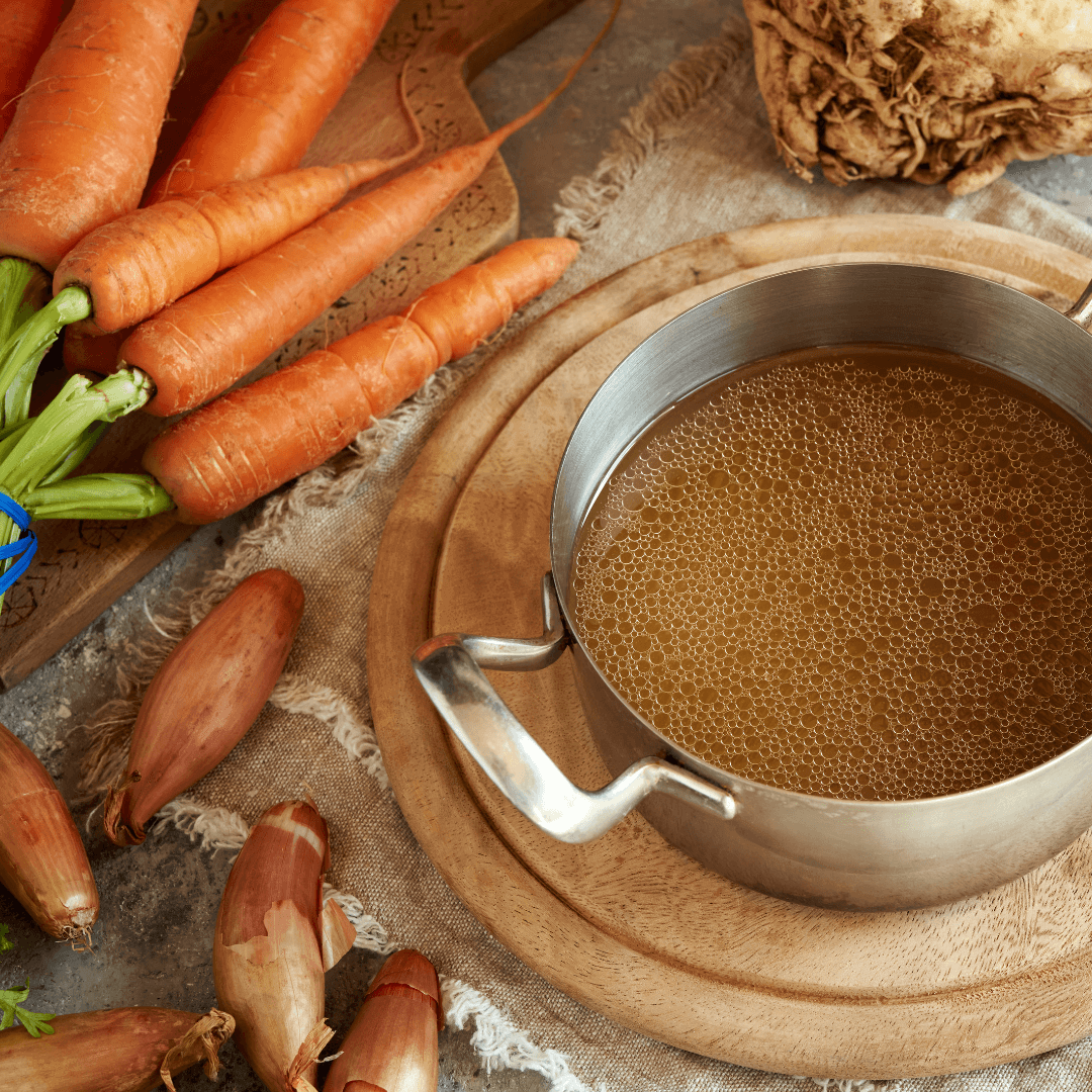 Vegetable stock in large pot with vegetables.