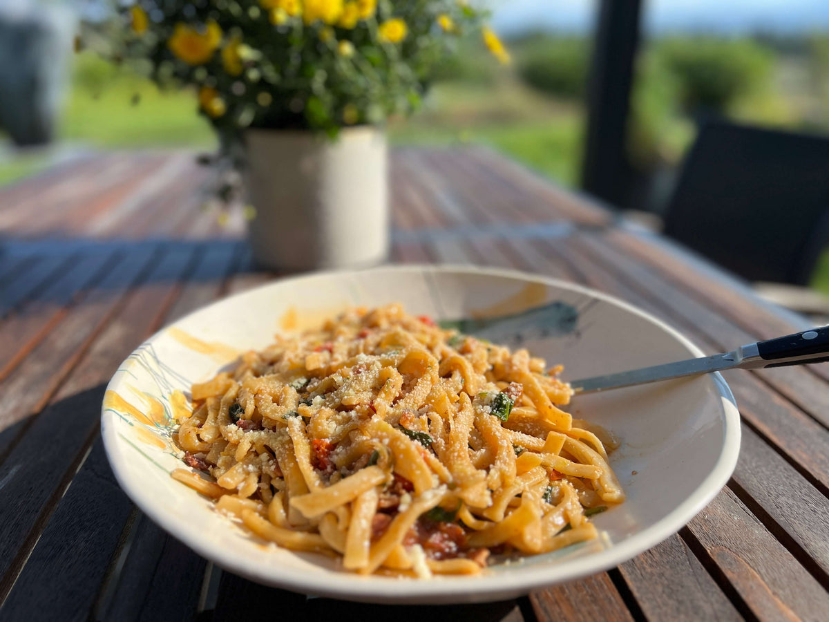 BLT noodles on a picnic table in the sun with sunflowers in the background