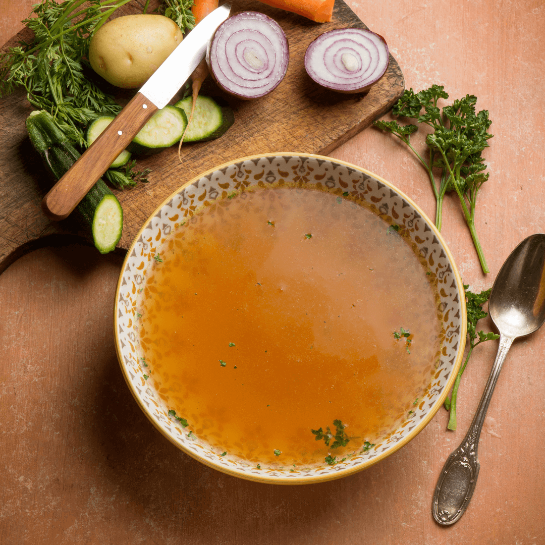 Brown stock in large bowl with vegetables.