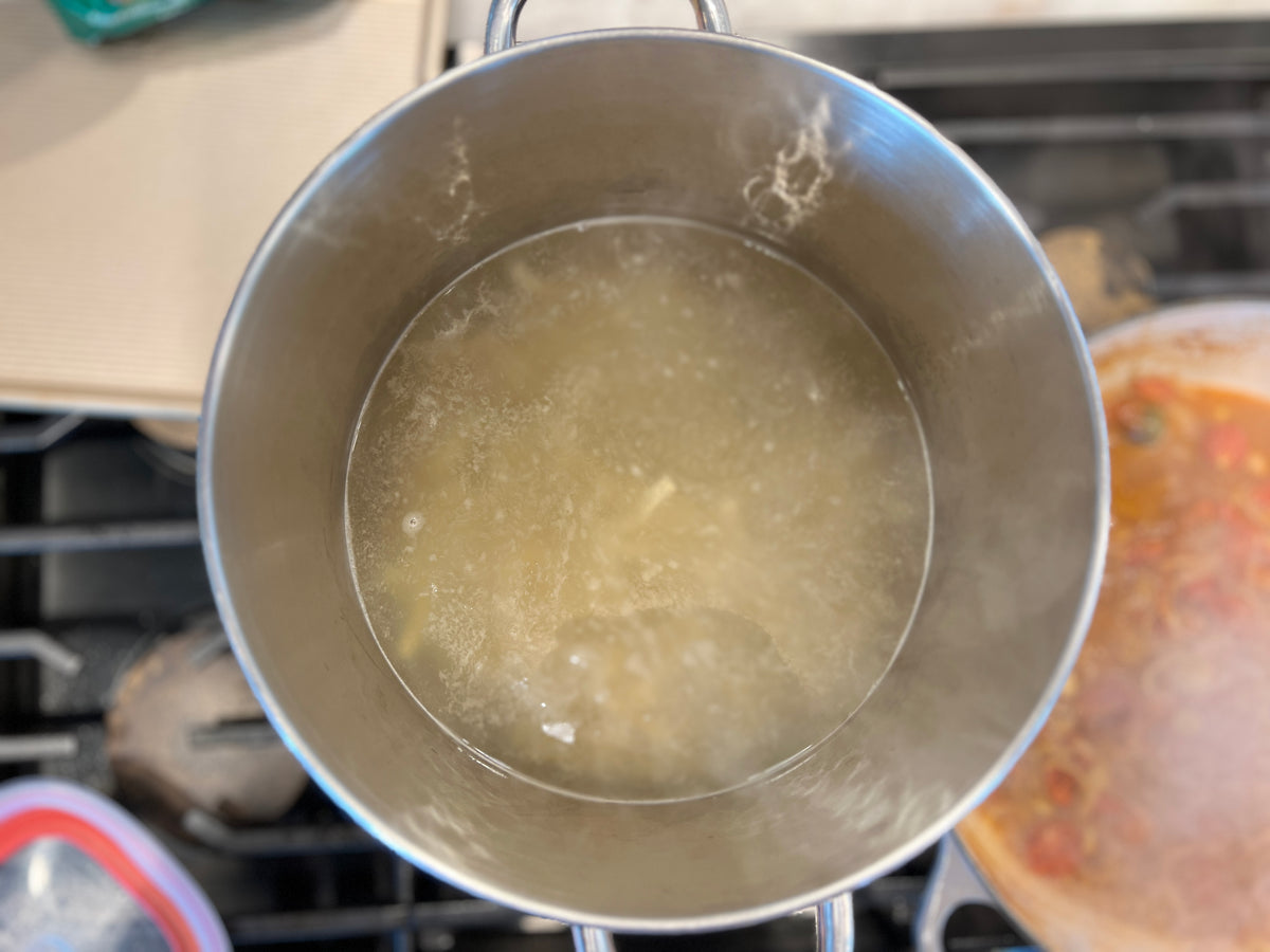 Frozen egg noodles boiling in a pot of water. 