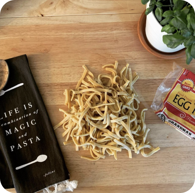 Egg noodles on a cutting board with basil and Grandma's packaging