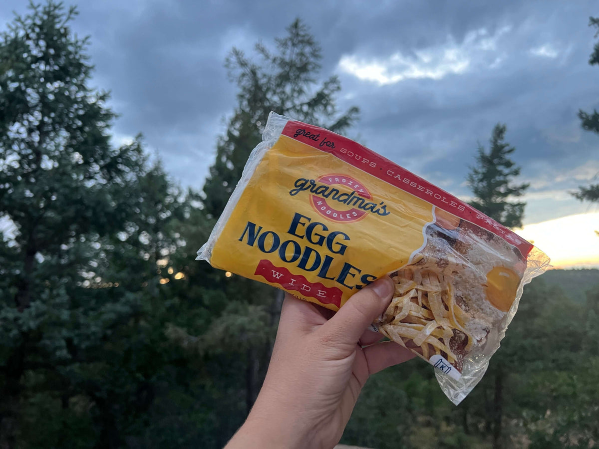 A customer holding a bag of Grandma's frozen egg noodles while on a camping trip.