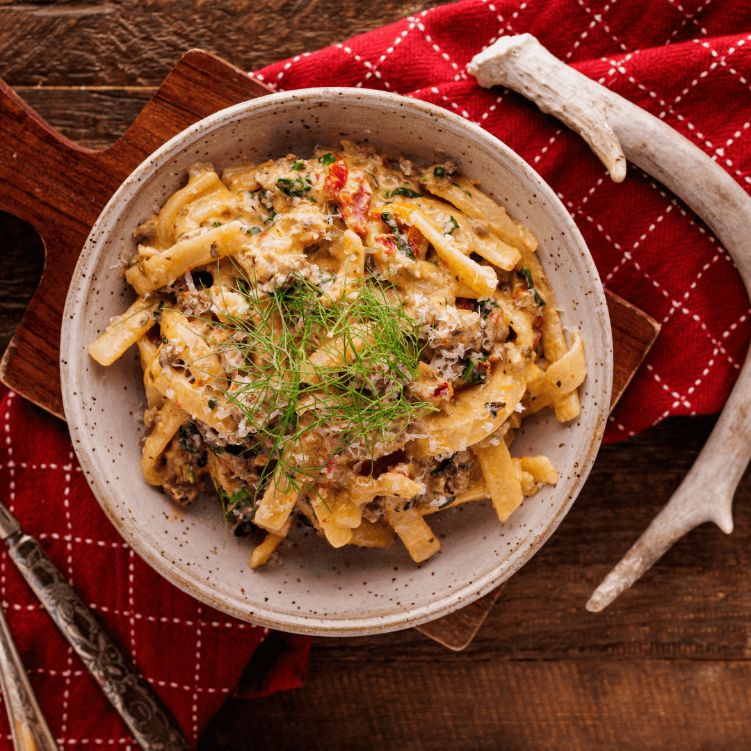 Fennel sausage and egg noodles in a bowl with garnish.